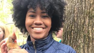 Sheridan Alford, smiling at the camera while holding a female Cardinal in her hands