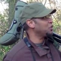 Dr. Drew Lanham in the outdoors with a birdwatching scope and tripod resting on his shoulder
